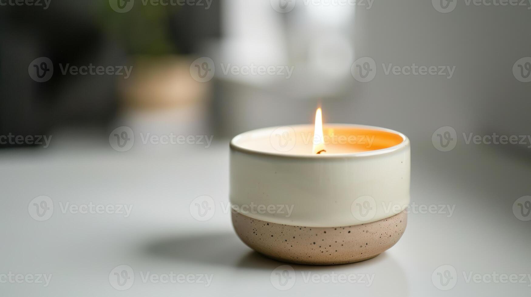 Modern pink and white candle is lit on a table, adding a warm glow to the space photo