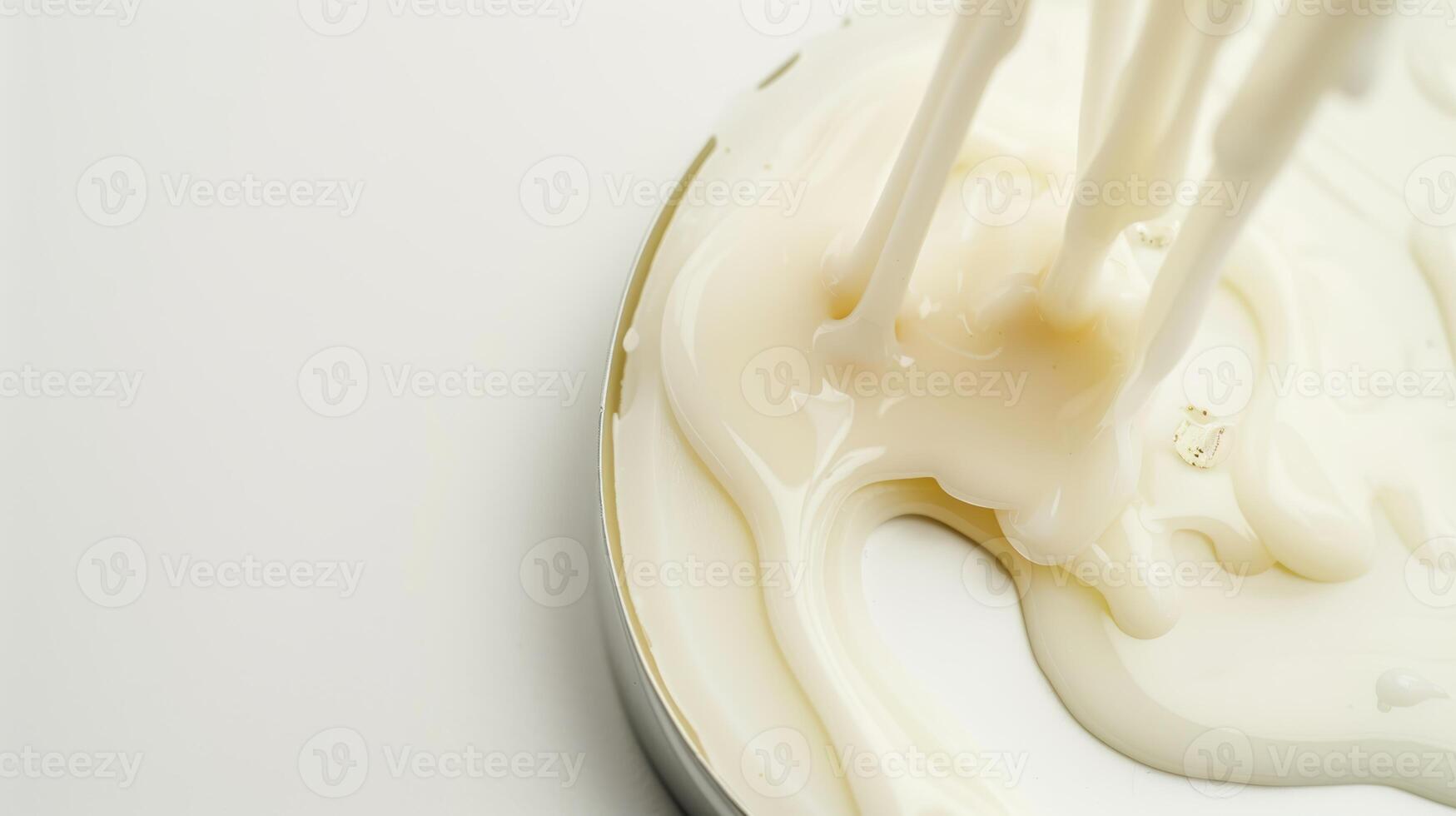 Smooth and luxurious thick white cream being poured into a container against a clean background, perfect for beauty, skincare, or dairy product concepts photo