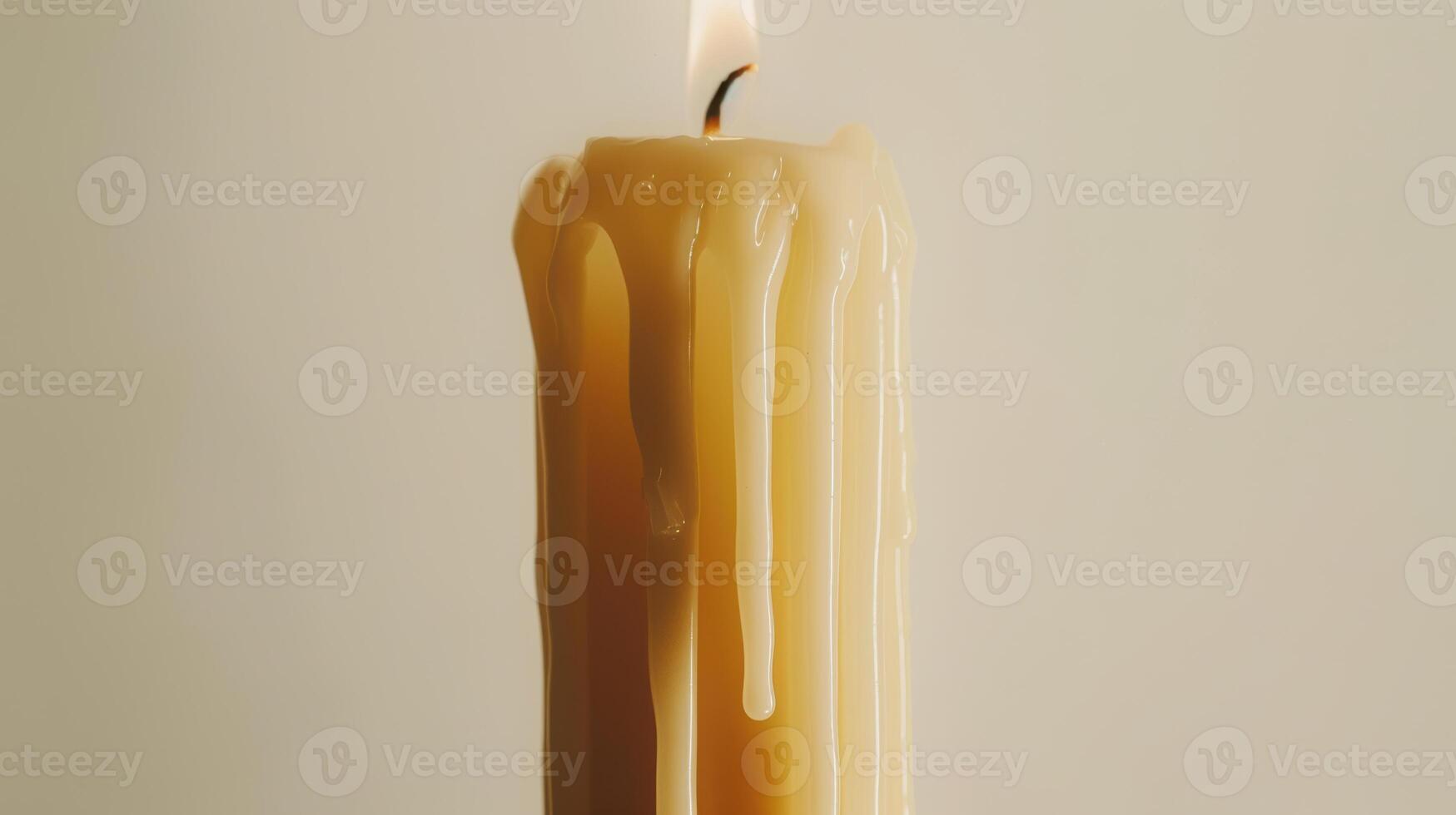 White candle is melting, forming fascinating patterns with its wax against a neutral backdrop photo