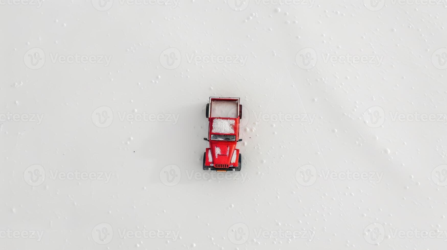 Red toy car sits on a snowy field, creating a festive winter scene photo