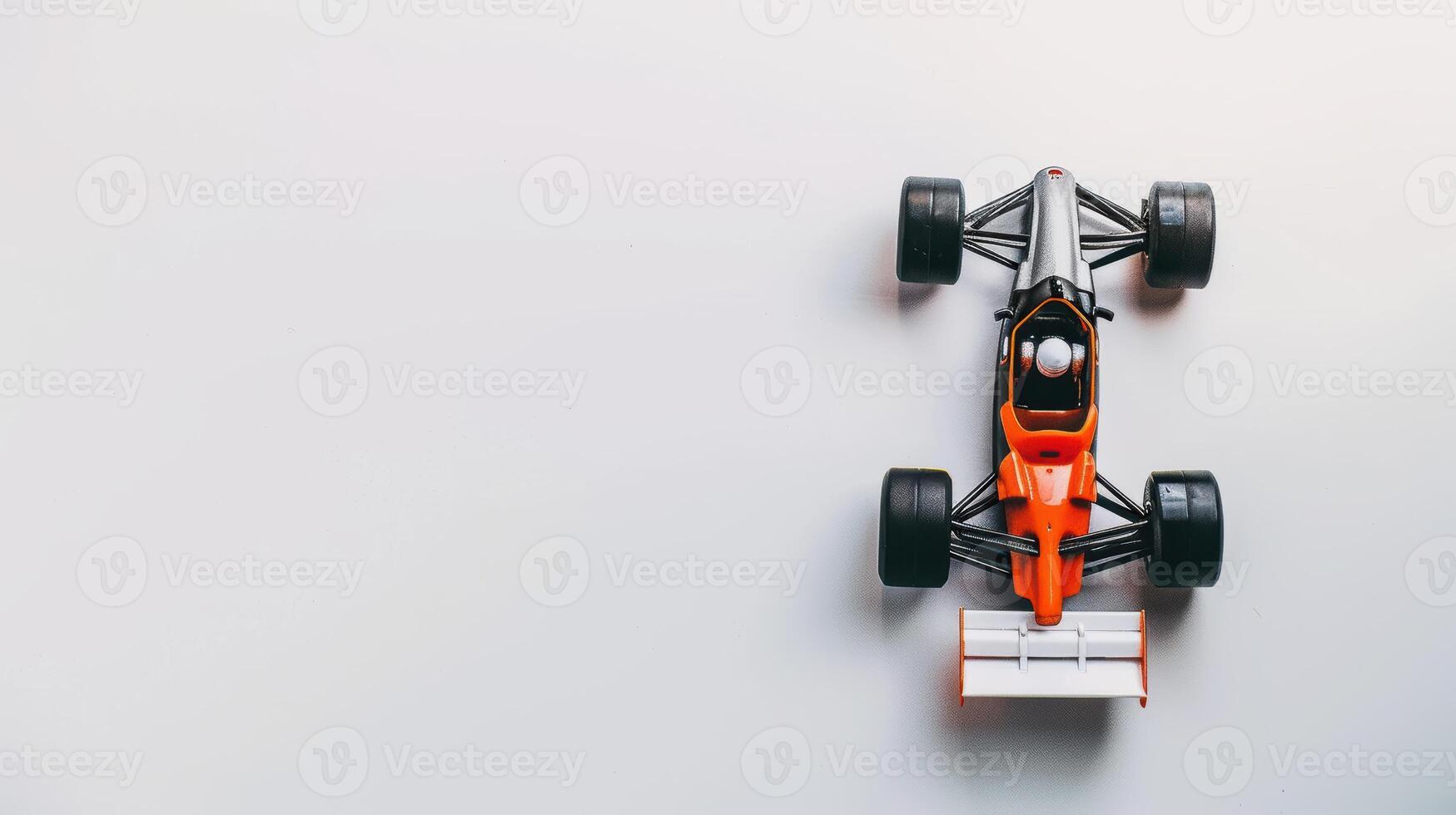 Black and orange toy race car displayed on a white background with empty space to the side photo