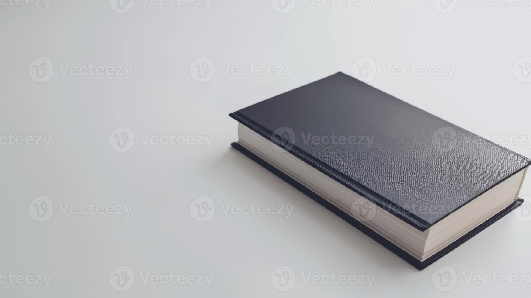 Black hardcover book rests on a white table, exuding simplicity and promise photo