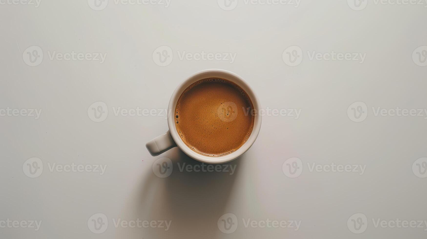 White coffee mug with foamy milk sitting on a white tabletop photo