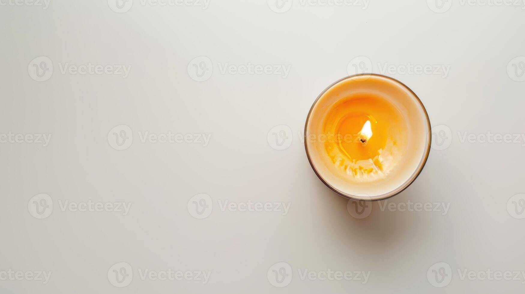Single scented candle burning on a white table, creating a warm and inviting ambiance photo