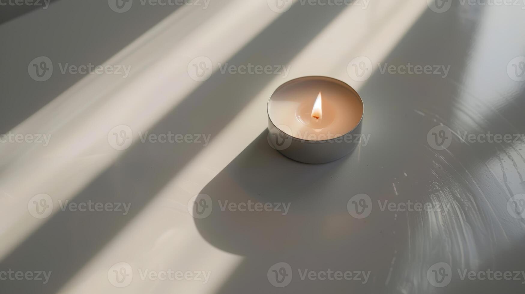 Lone scented candle flickers on a white table, casting shadows in the soft window light photo