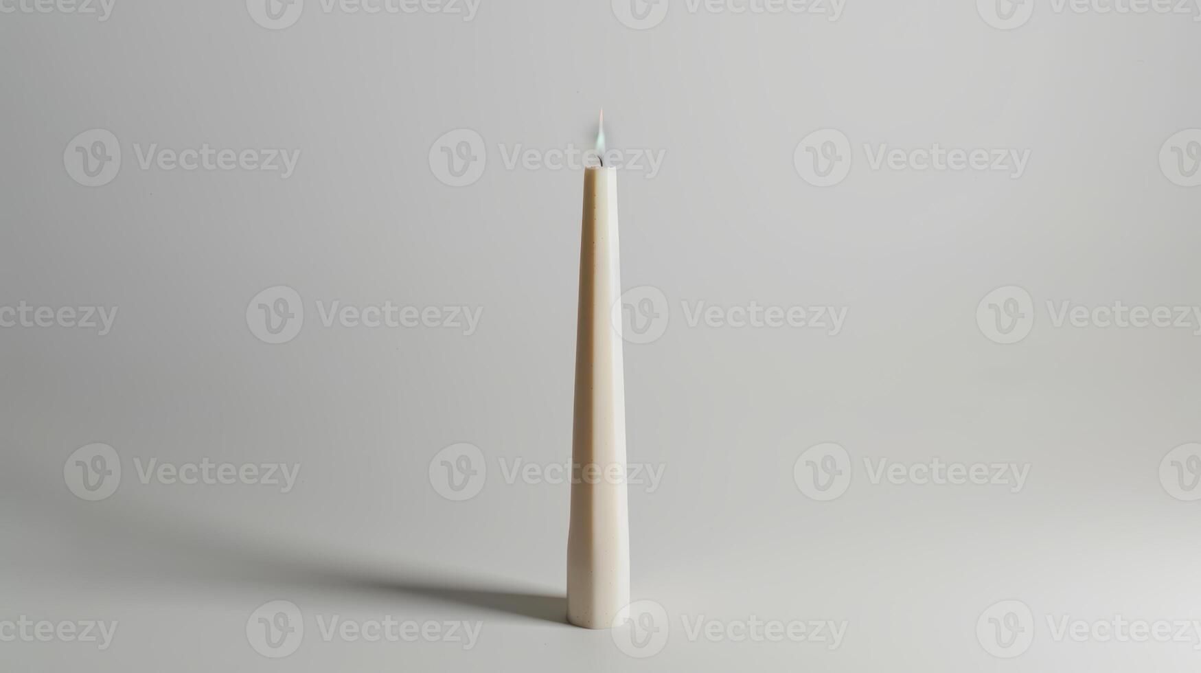Solitary white candle illuminates a serene white backdrop, evoking feelings of calm and serenity photo