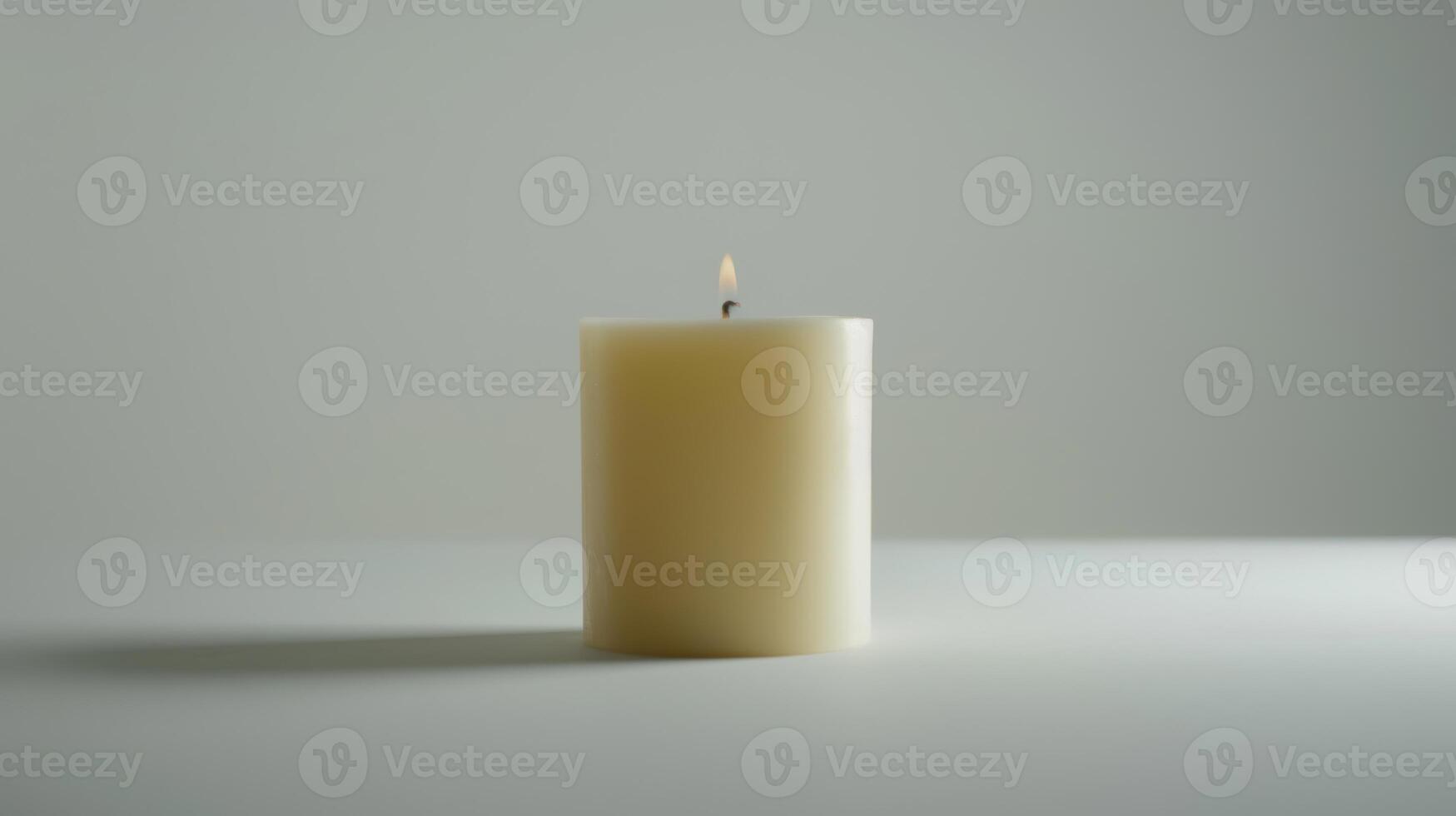 Solitary white candle illuminates a white surface with its inviting and cozy glow photo