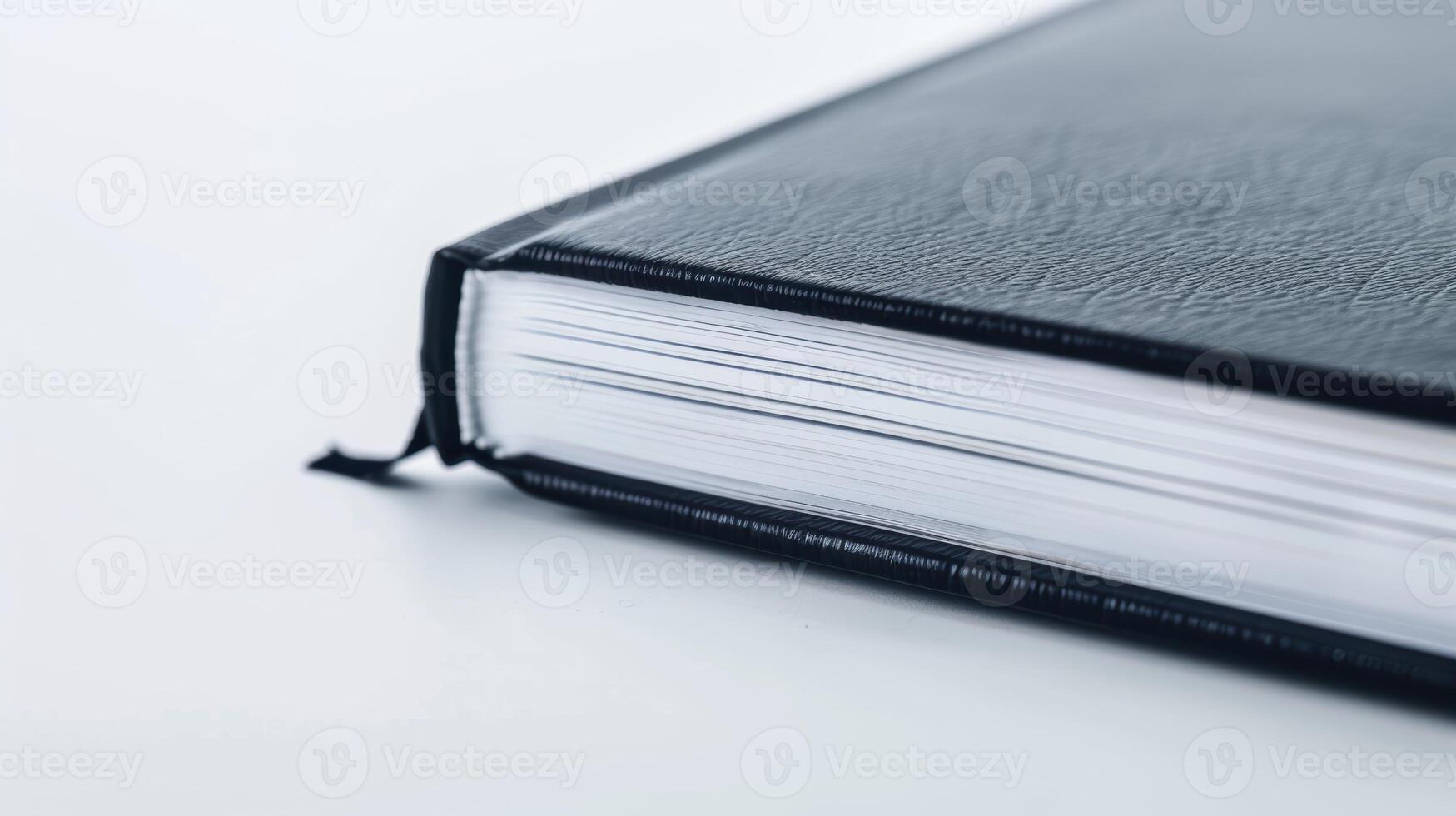 Black leather-bound thick book resting on white surface, displaying its blank pages photo