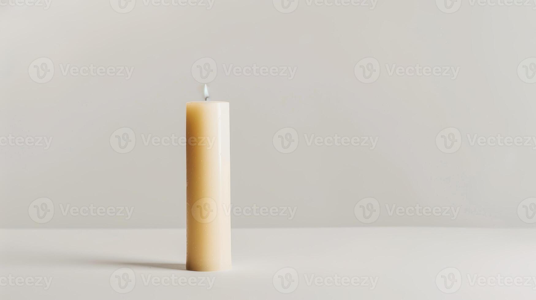 Solitary white candle illuminates a pristine white surface, creating a serene backdrop photo