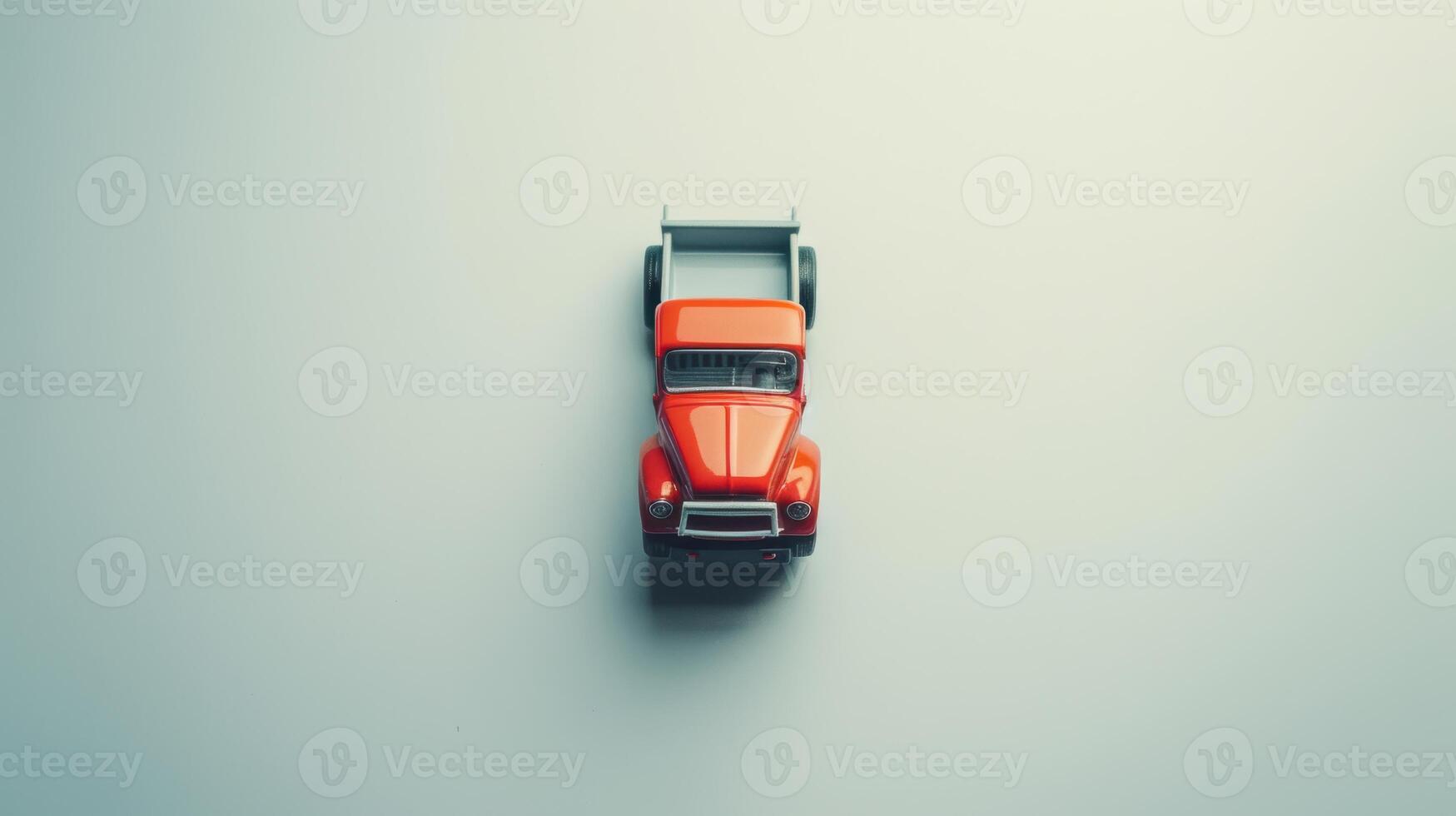Small red toy pickup truck sits on a simple backdrop, creating a soft shadow photo