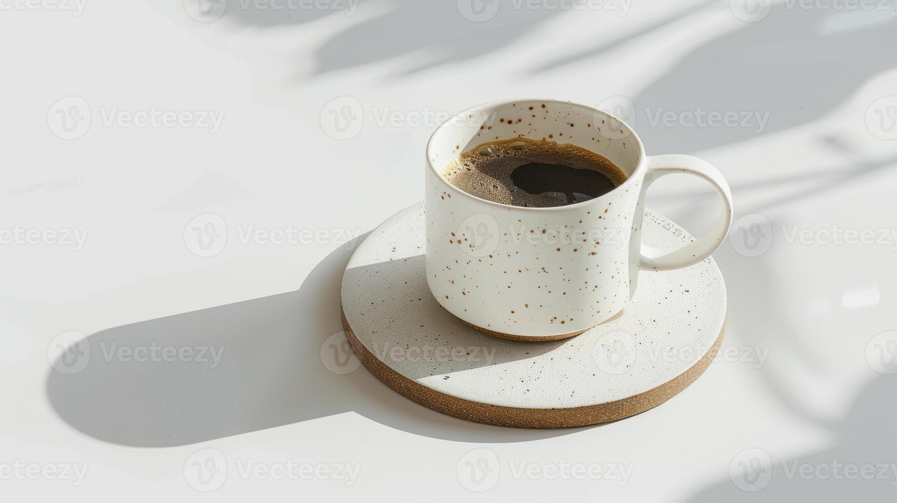 Cup of coffee sits on a white table, casting shadows from the sun shining through a nearby window photo