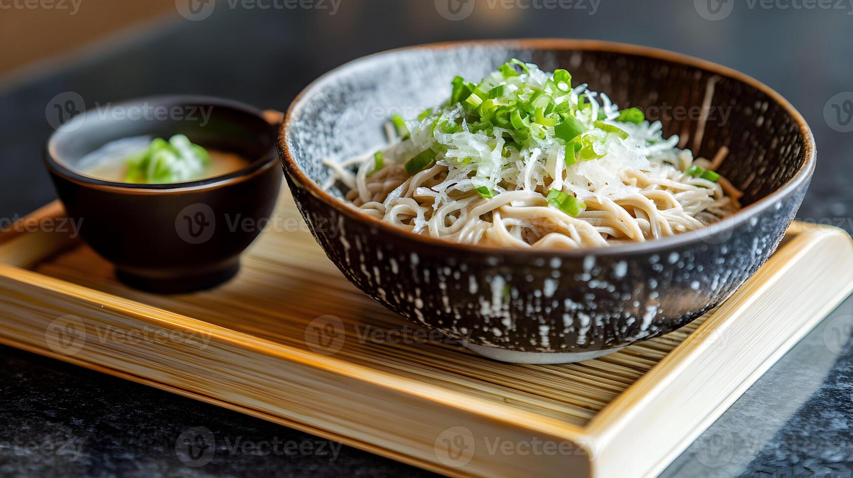 A bowl of chilled zaru soba noodles served on a bamboo tray with a small dish of dipping sauce, garnished with finely chopped green onions and grated daikon photo