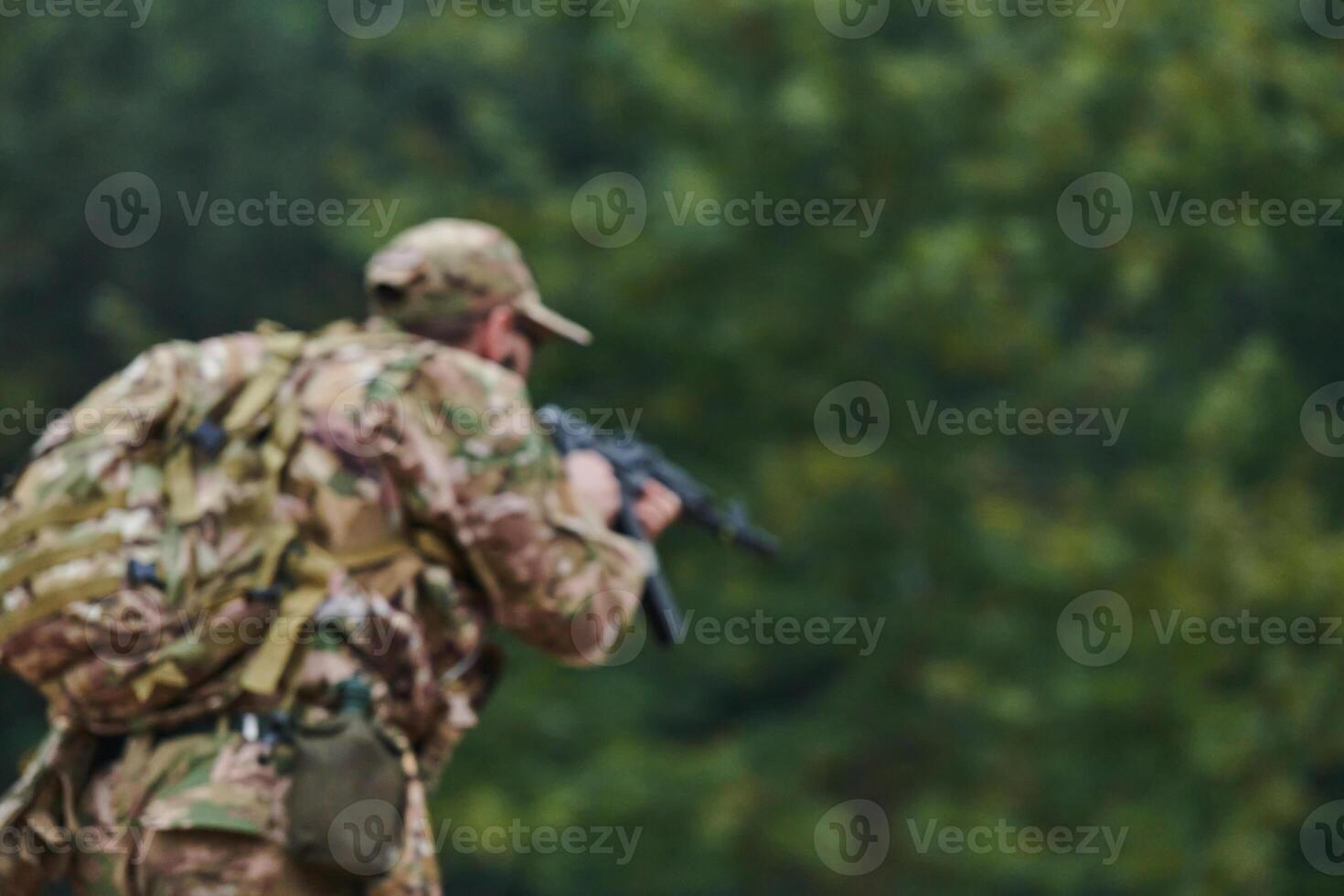 An elite soldier, camouflaged and stealthily navigating through dangerous woodland terrain, executes a covert mission in a secluded forest area photo