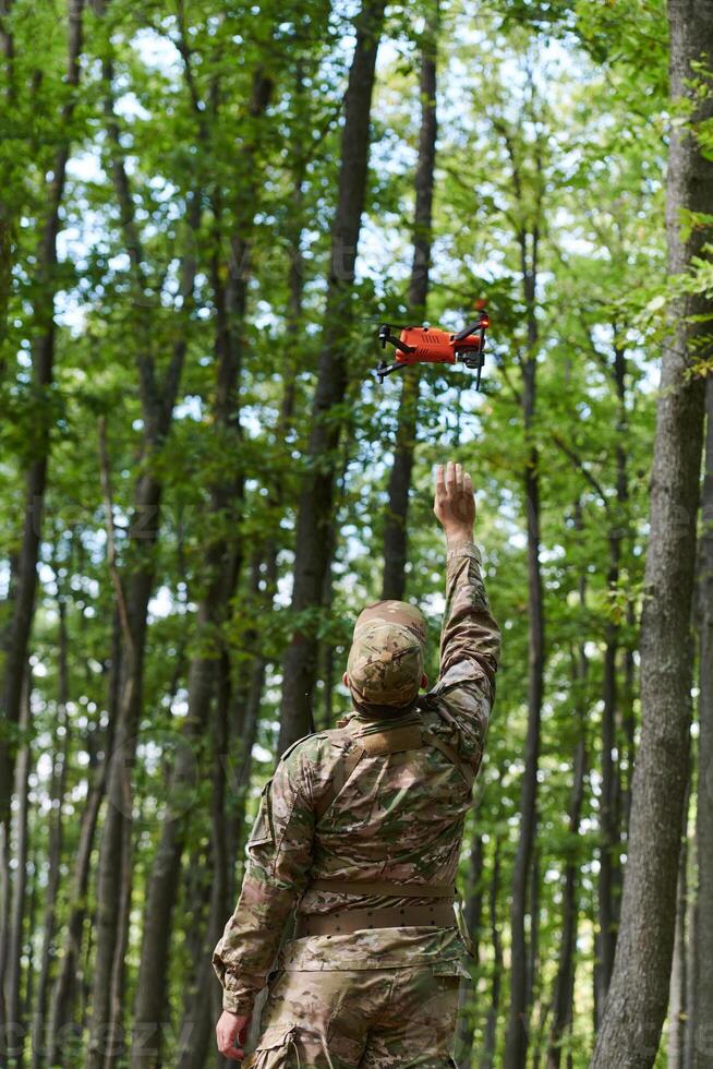 Elite military unit, equipped with state-of-the-art technology including a drone, strategically navigates and surveys dangerous wooded terrain, showcasing their precision, cooperation, and specialized photo