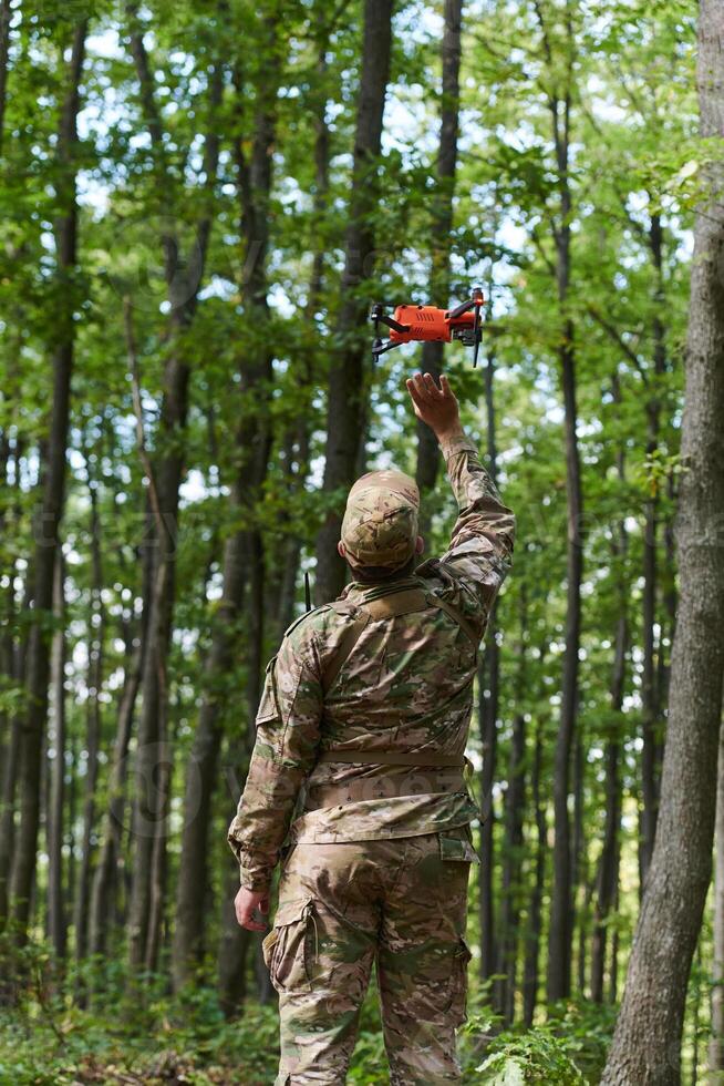 Elite military unit, equipped with state-of-the-art technology including a drone, strategically navigates and surveys dangerous wooded terrain, showcasing their precision, cooperation, and specialized photo