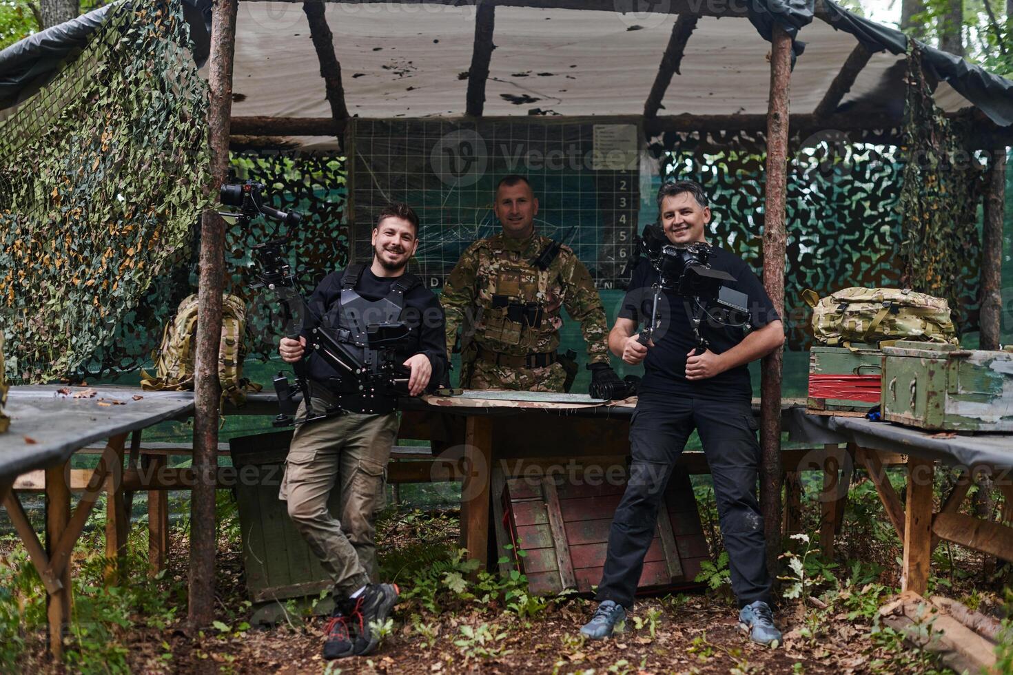Two videographers collaborate seamlessly, capturing moments with a military major at his base, illustrating a harmonious blend of technology, media, and military communication in the production of a photo