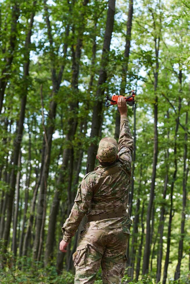 Elite military unit, equipped with state-of-the-art technology including a drone, strategically navigates and surveys dangerous wooded terrain, showcasing their precision, cooperation, and specialized photo