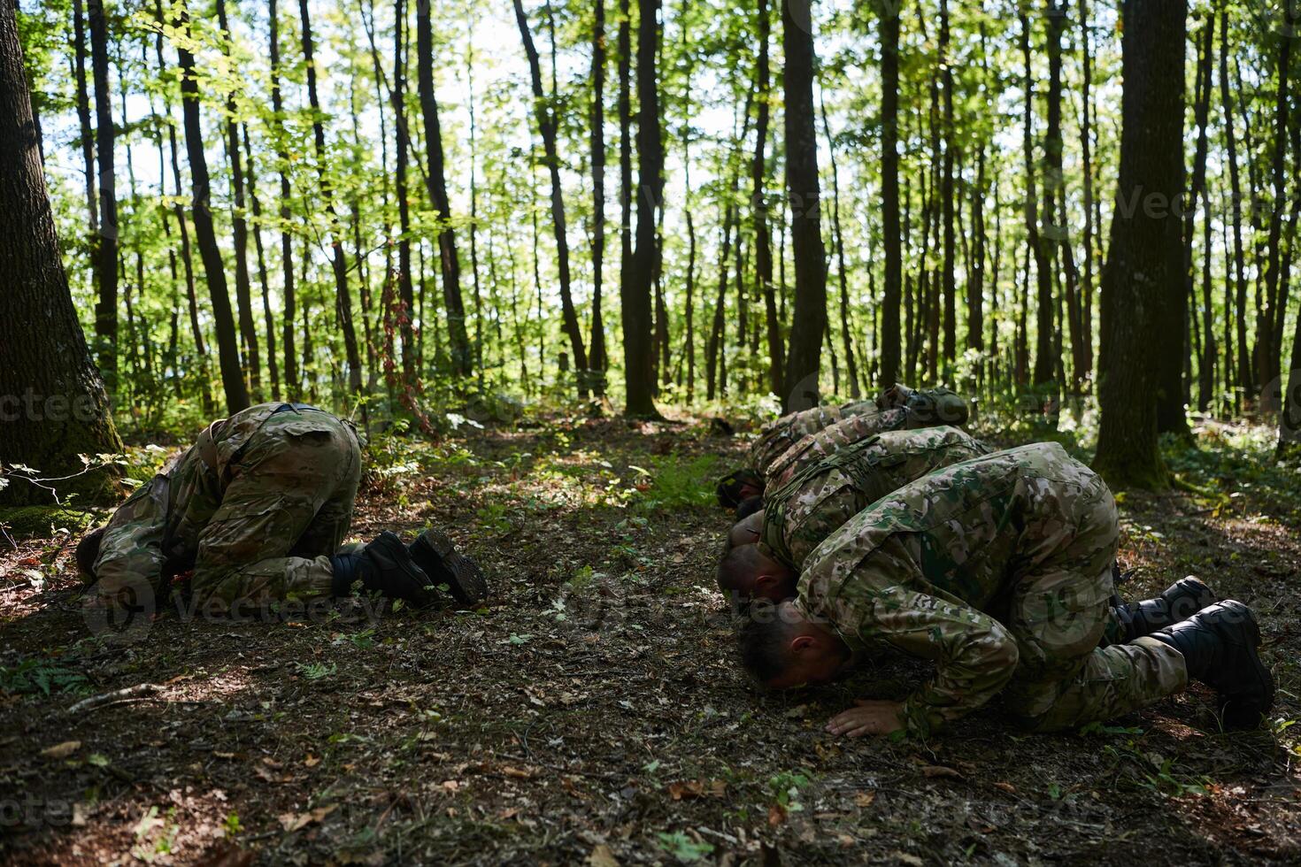A dedicated group of soldiers engages in Islamic prayer amidst the challenging and perilous conditions of a military operation in dense forested areas photo