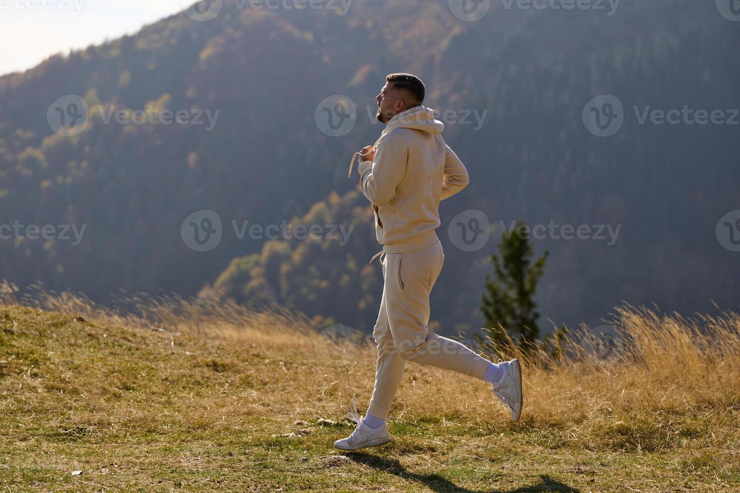 A handsome man maintains his healthy lifestyle as he runs along beautiful natural trails, embodying the essence of fitness, wellness, and vitality in the midst of scenic outdoor surroundings. photo