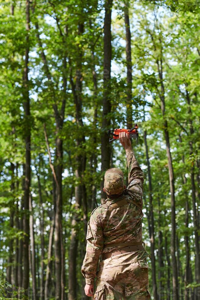 Elite military unit, equipped with state-of-the-art technology including a drone, strategically navigates and surveys dangerous wooded terrain, showcasing their precision, cooperation, and specialized photo