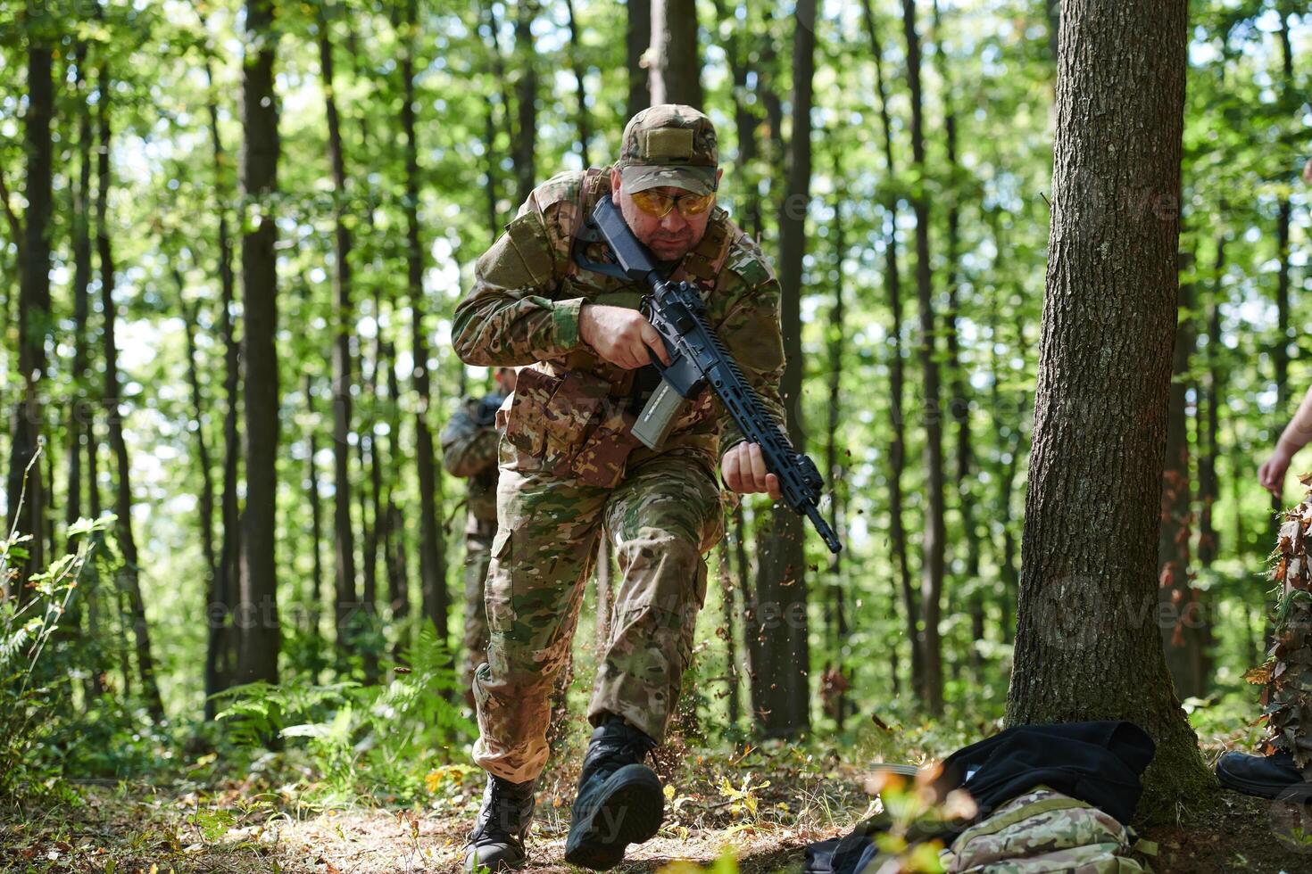 An elite soldier, camouflaged and stealthily navigating through dangerous woodland terrain, executes a covert mission in a secluded forest area photo