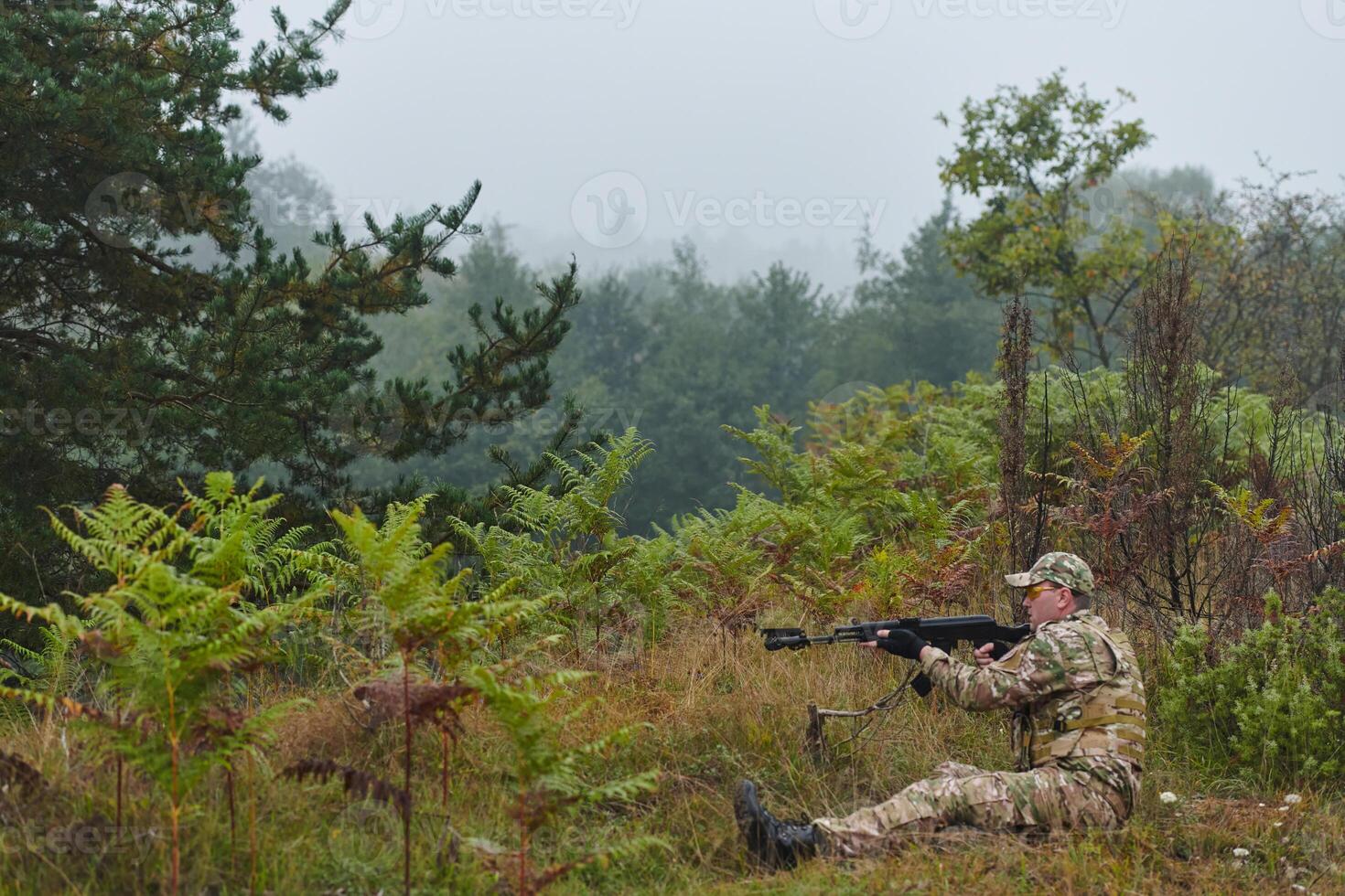 An elite soldier, camouflaged and stealthily navigating through dangerous woodland terrain, executes a covert mission in a secluded forest area photo