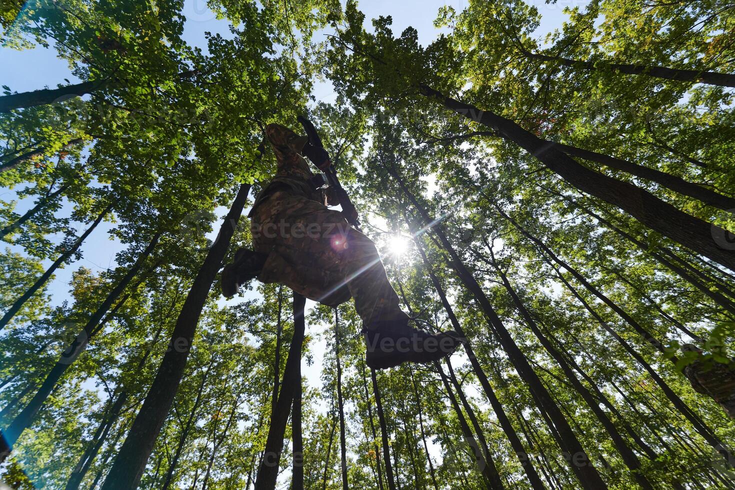 An elite soldier adeptly clears military barriers in the perilous wooded terrain, showcasing tactical skill and agility during specialized training photo