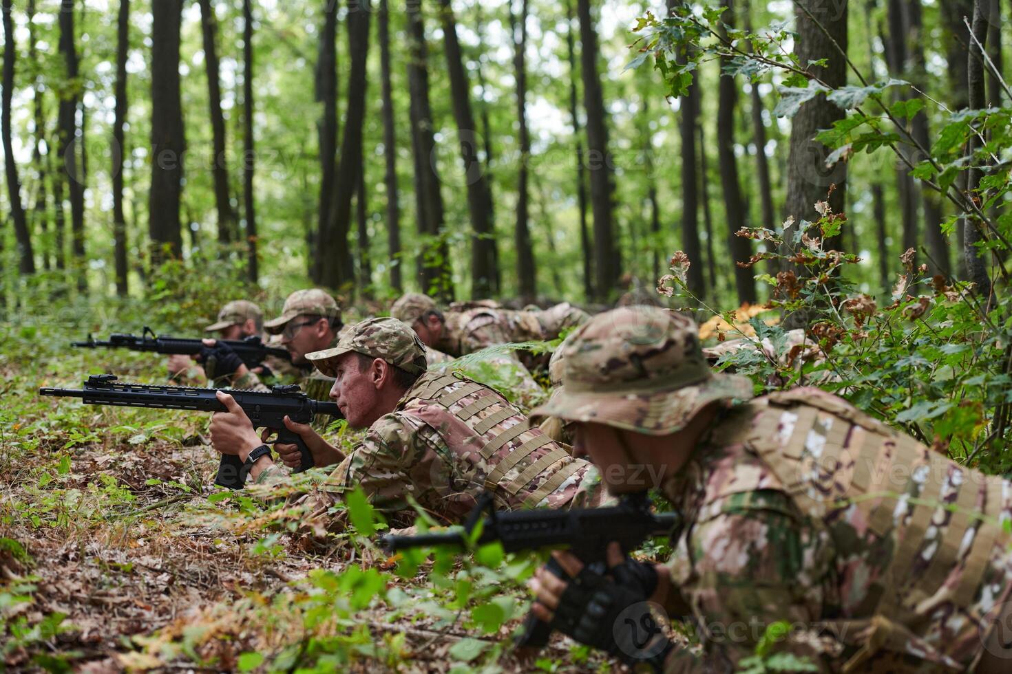 Elite soldiers stealthily maneuver through the dense forest, camouflaged in specialized gear, as they embark on a covert and strategic military mission photo
