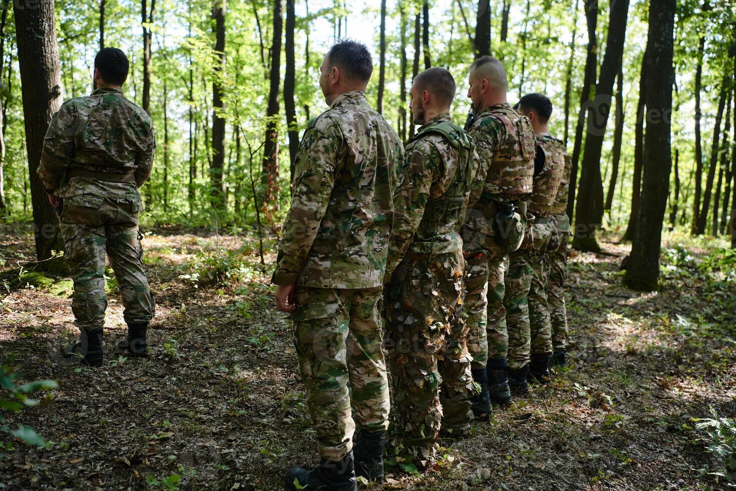 A dedicated group of soldiers engages in Islamic prayer amidst the challenging and perilous conditions of a military operation in dense forested areas photo