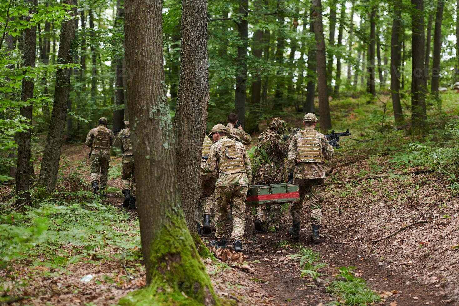 Elite military unit, cloaked in camouflage, transports a crate of ammunition through the dense forest, epitomizing strategic readiness and precision in their covert mission photo
