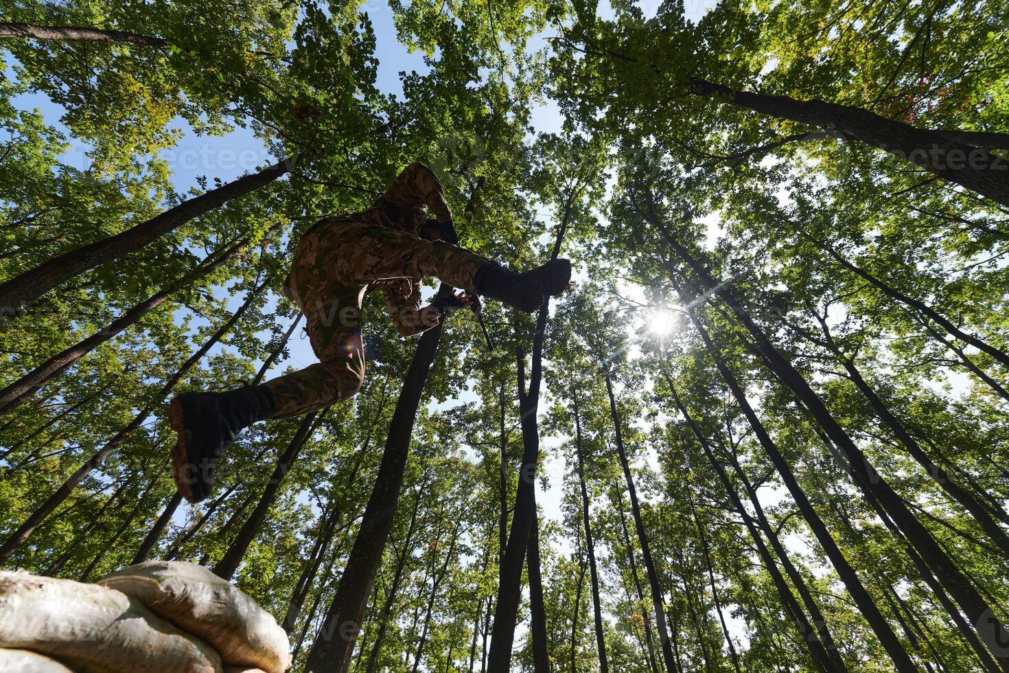 An elite soldier adeptly clears military barriers in the perilous wooded terrain, showcasing tactical skill and agility during specialized training photo