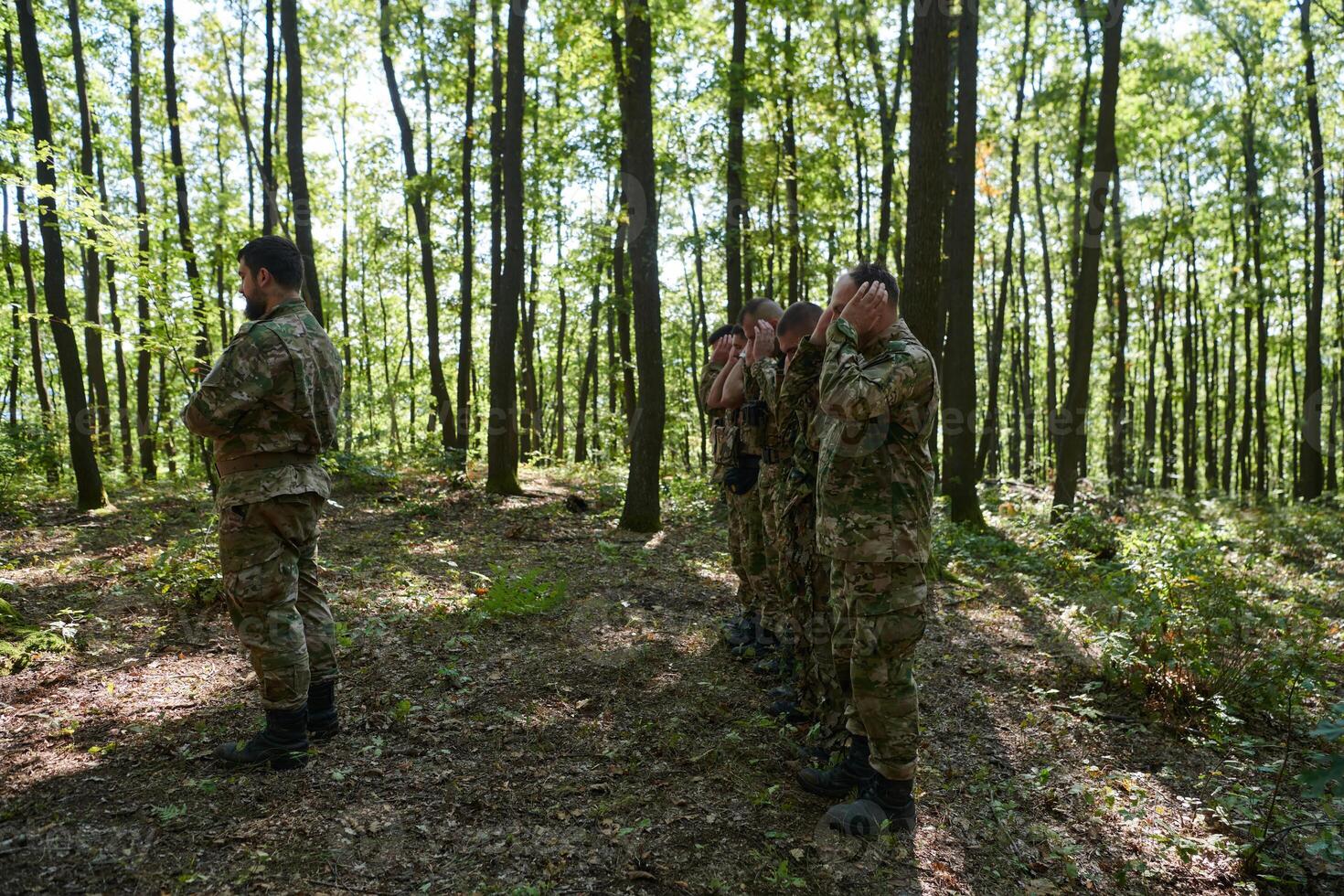 A dedicated group of soldiers engages in Islamic prayer amidst the challenging and perilous conditions of a military operation in dense forested areas photo