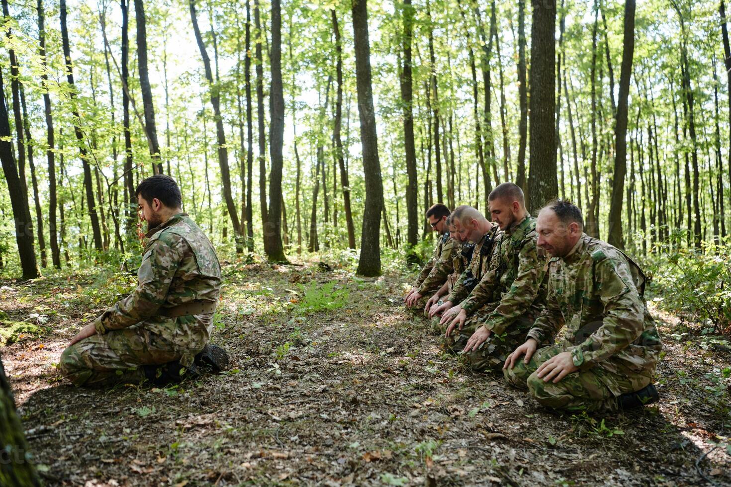 A dedicated group of soldiers engages in Islamic prayer amidst the challenging and perilous conditions of a military operation in dense forested areas photo
