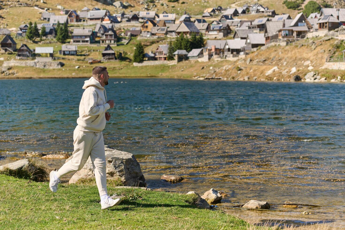 Athletic man maintains his healthy lifestyle by running through the scenic mountain and lakeside environment, showcasing a commitment to fitness and well-being photo