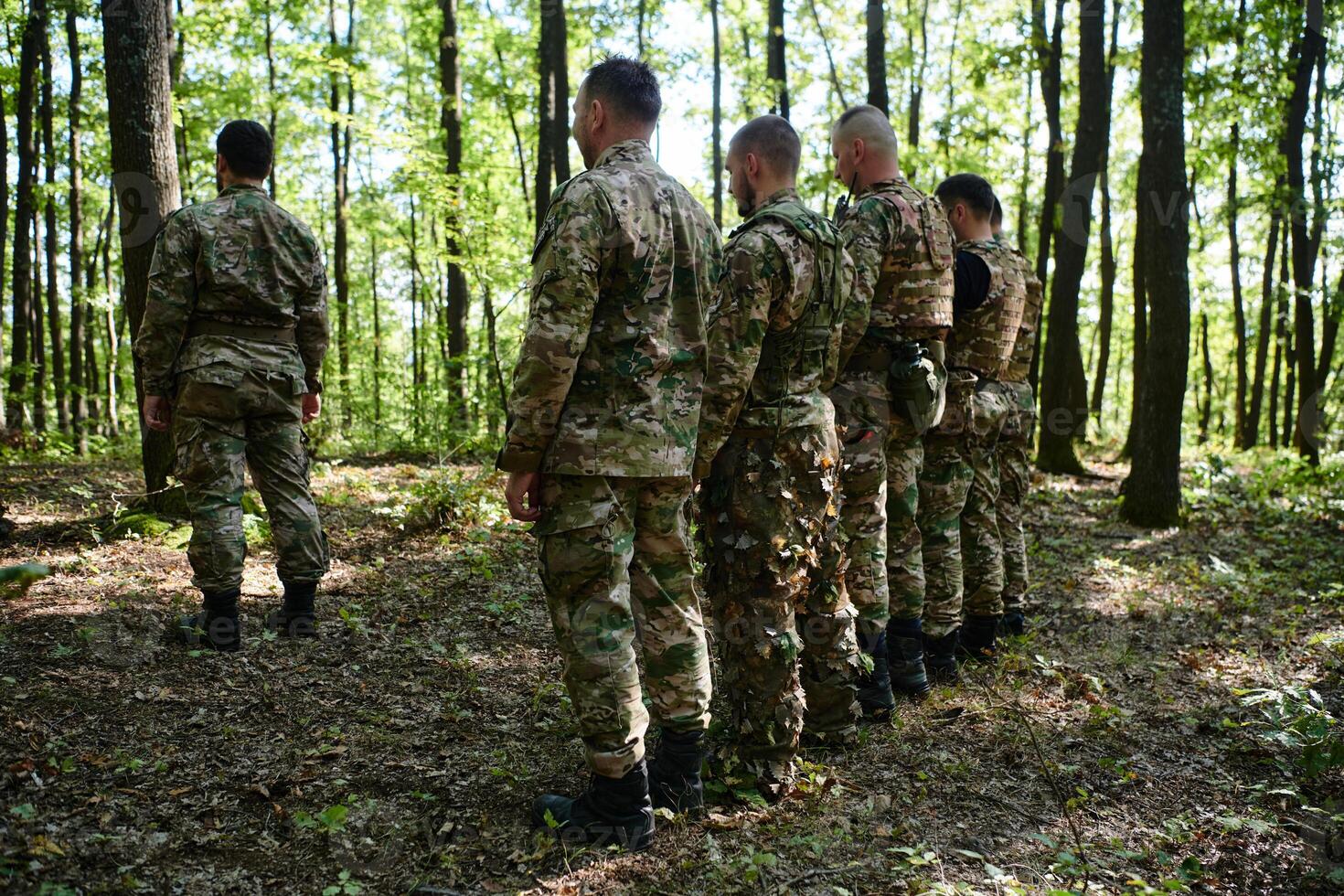 A dedicated group of soldiers engages in Islamic prayer amidst the challenging and perilous conditions of a military operation in dense forested areas photo