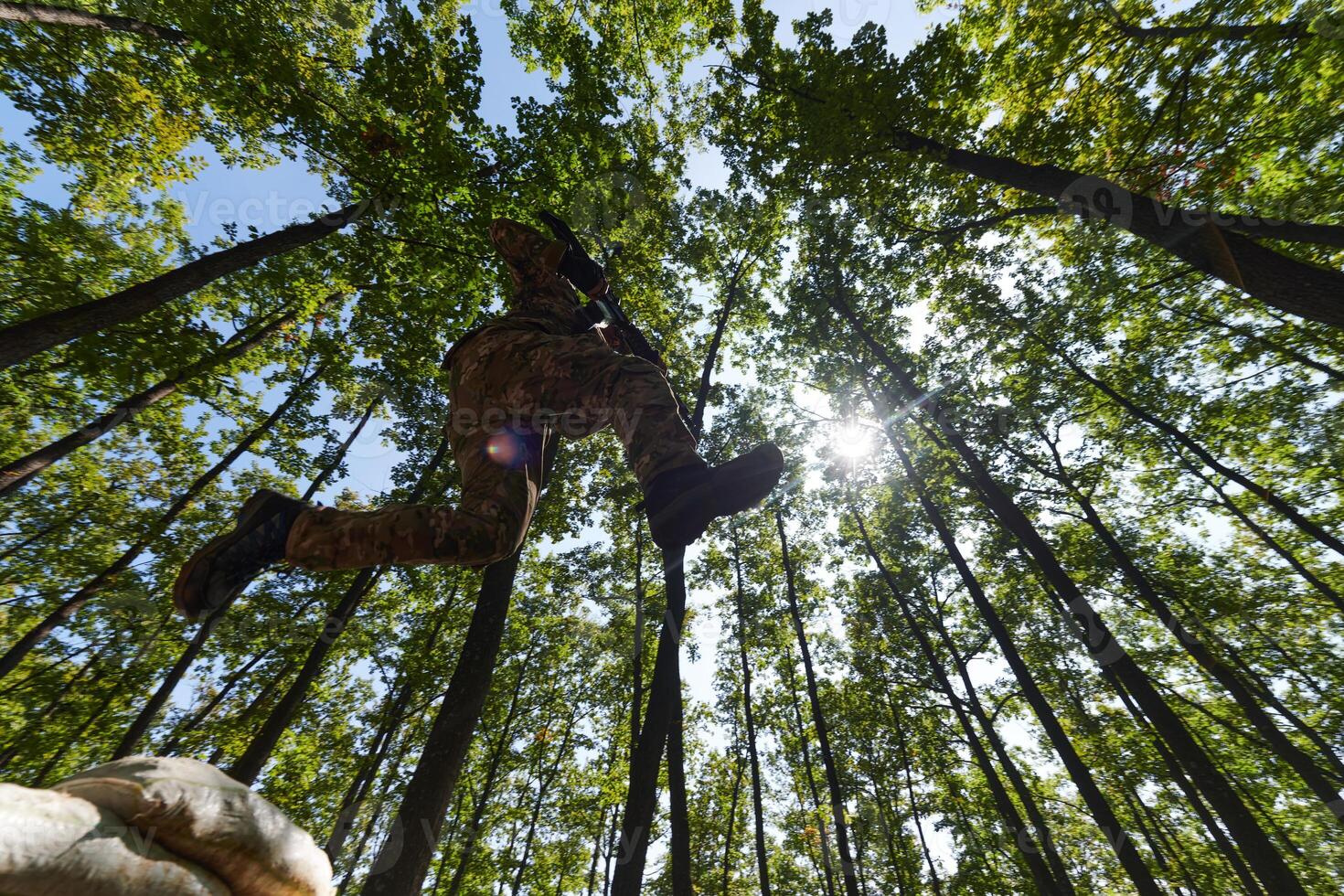 An elite soldier adeptly clears military barriers in the perilous wooded terrain, showcasing tactical skill and agility during specialized training photo