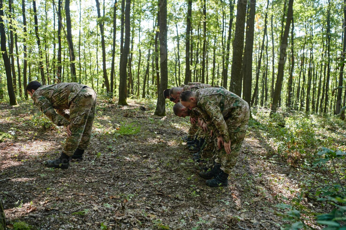 A dedicated group of soldiers engages in Islamic prayer amidst the challenging and perilous conditions of a military operation in dense forested areas photo