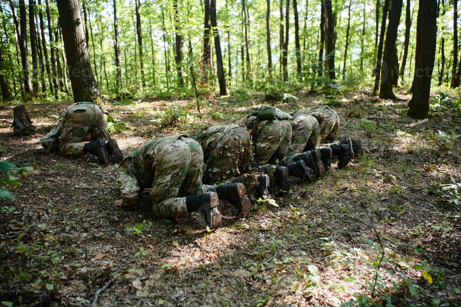 A dedicated group of soldiers engages in Islamic prayer amidst the challenging and perilous conditions of a military operation in dense forested areas photo