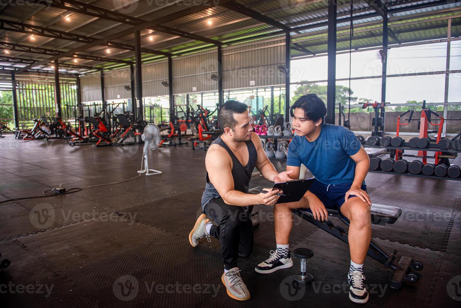 male trainer is planning an exercise program for a client who wants to improve their physical shape in a fitness center photo