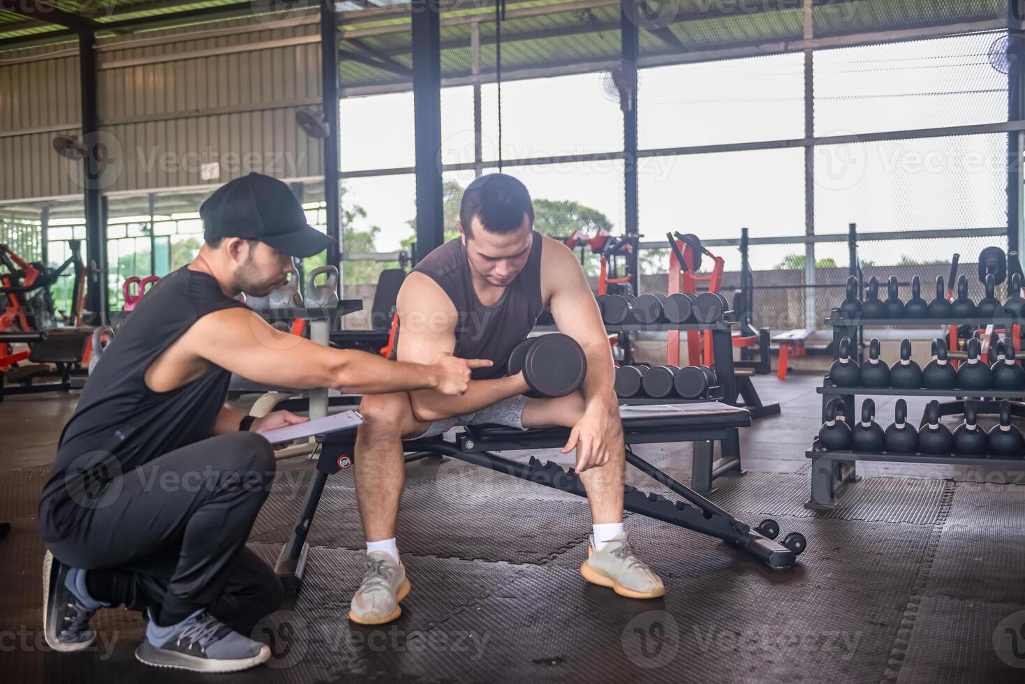 male trainer is planning an exercise program for a client who wants to improve their physical shape in a fitness center photo