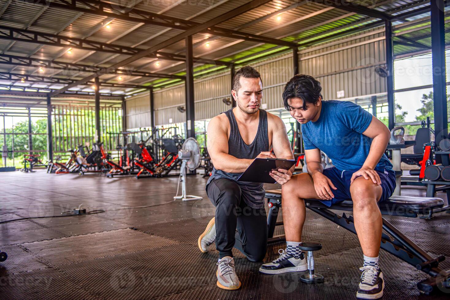 male trainer is planning an exercise program for a client who wants to improve their physical shape in a fitness center photo