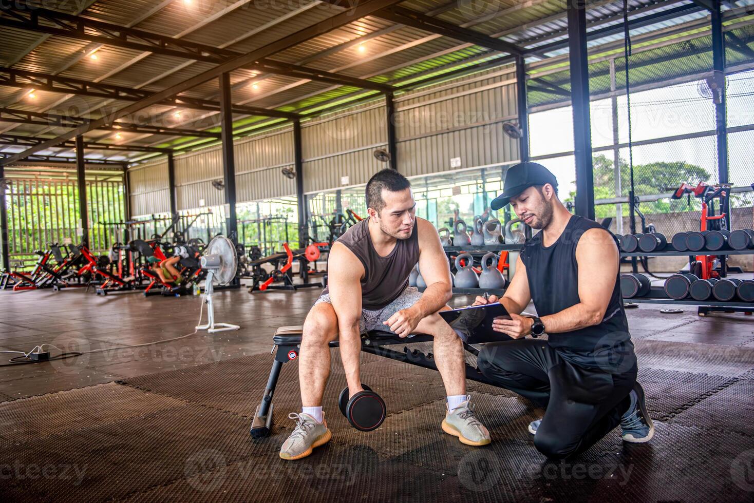 male trainer is planning an exercise program for a client who wants to improve their physical shape in a fitness center photo