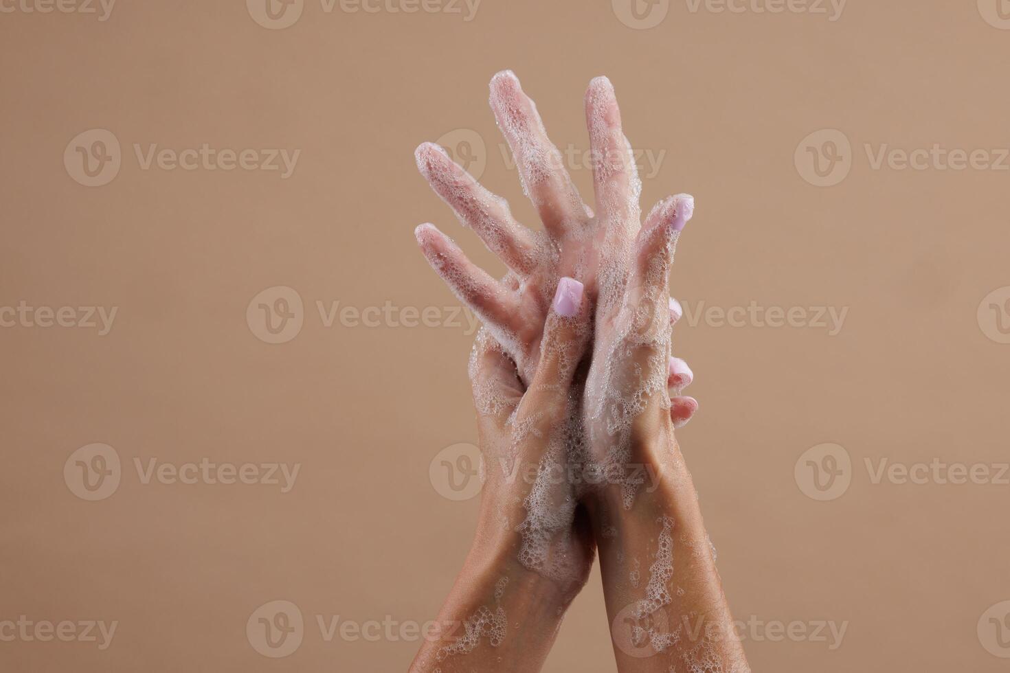 Woman washing hands with soap on color background photo
