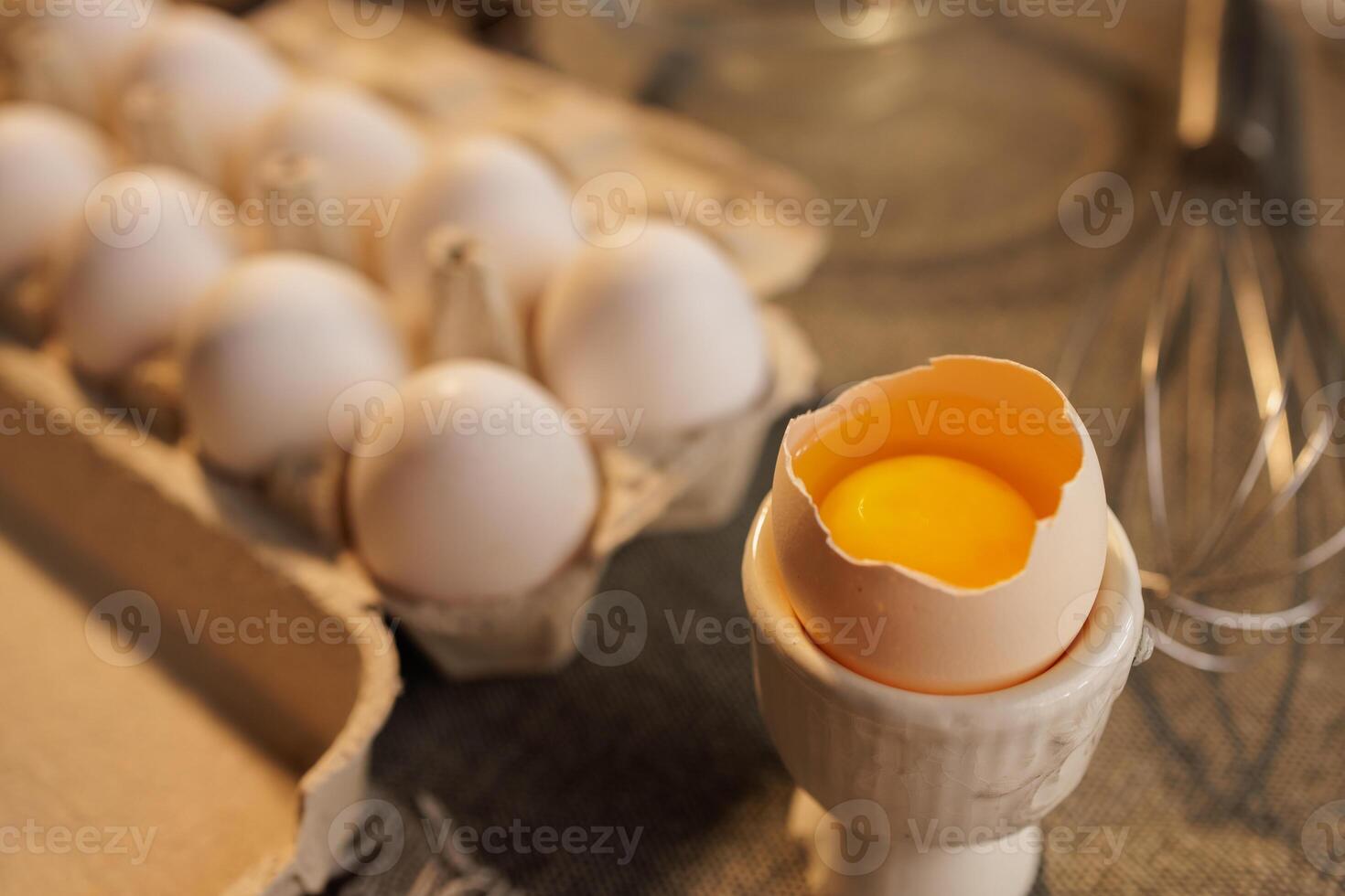 large broken chicken egg in a special container on the background of a box with eggs photo