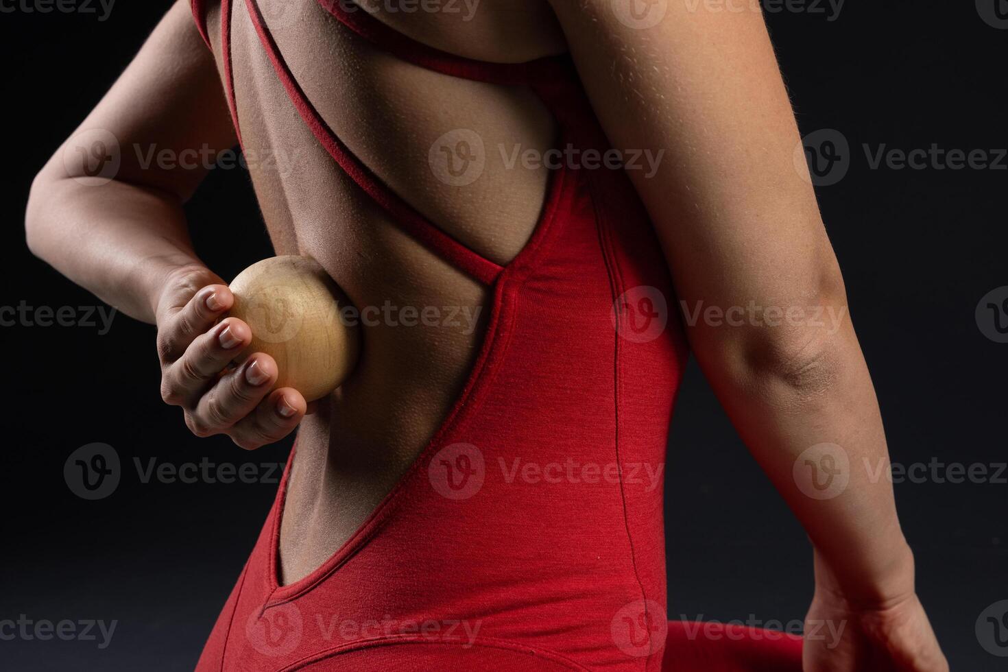 girl doing back muscle massage with wooden yoga ball close up, self massage tool photo