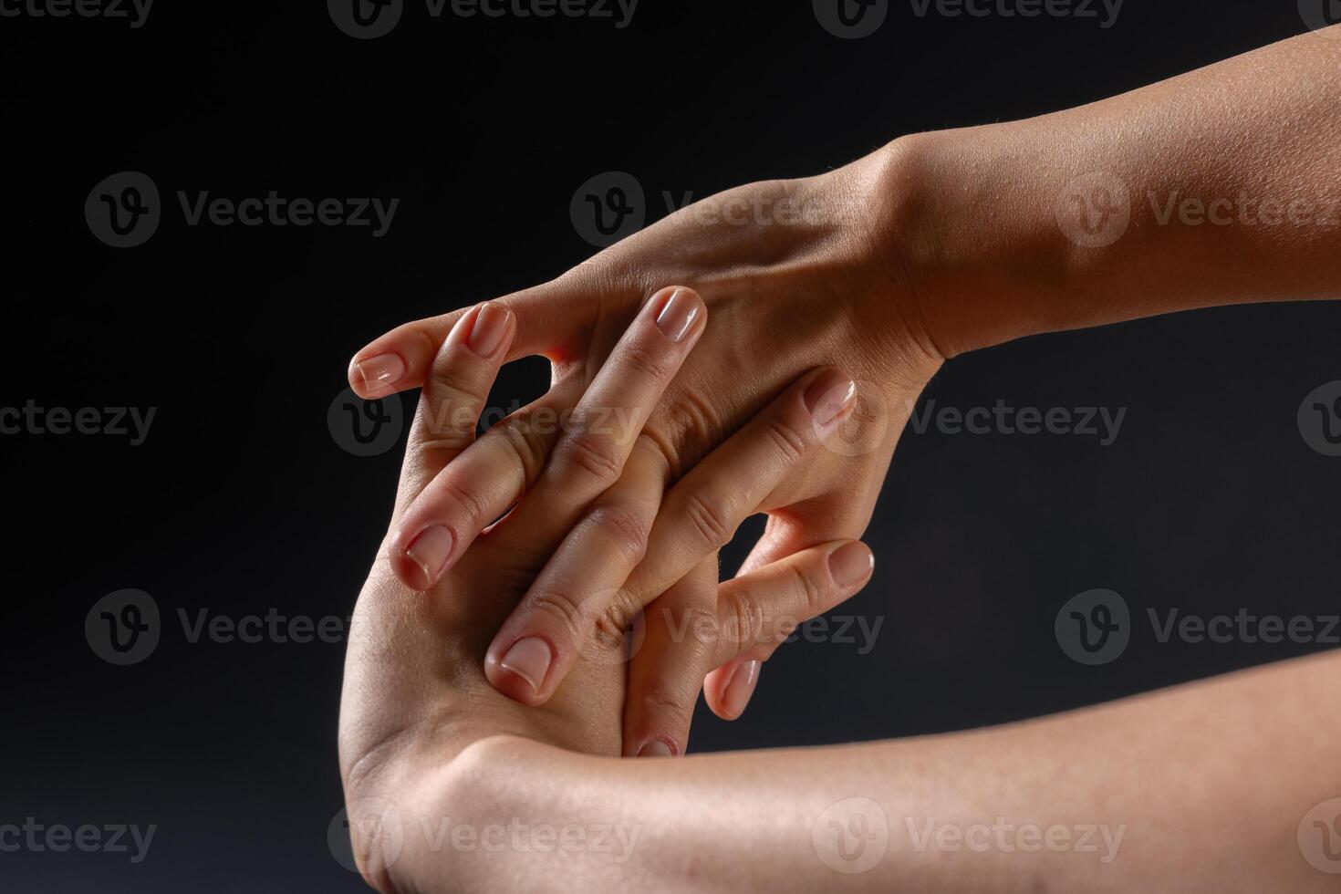 close up of female hands doing hand stretching on dark background, hand warm up concept photo