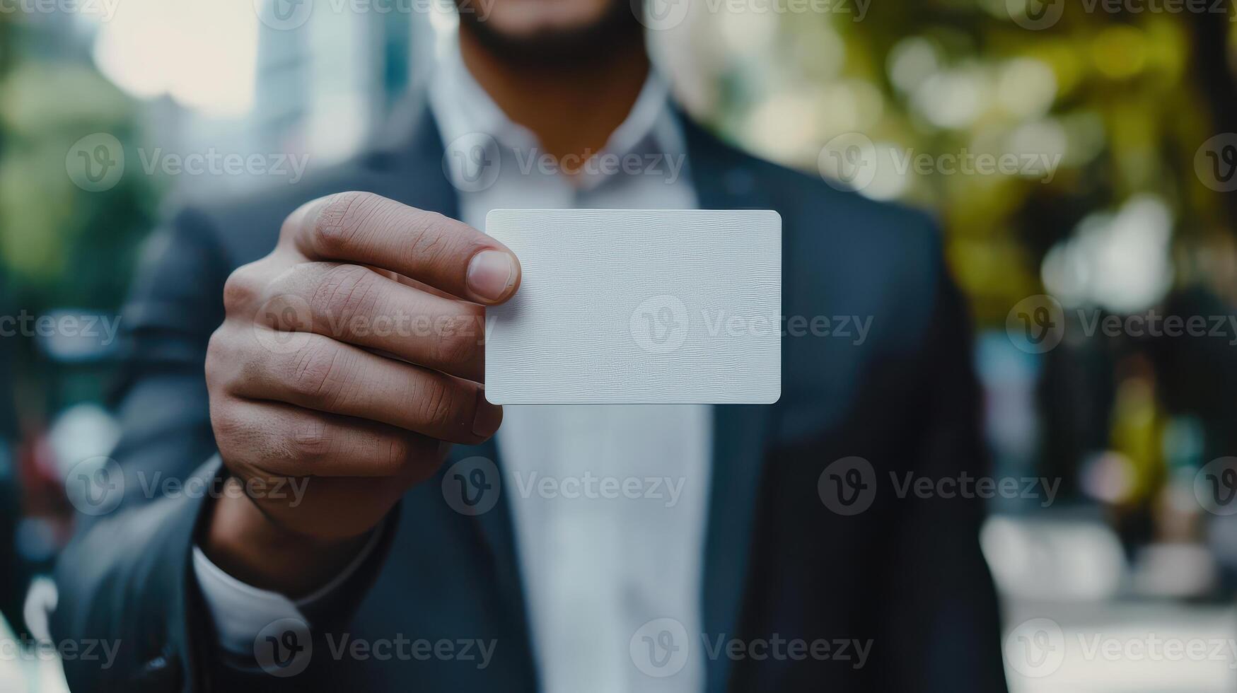 A man in a suit holding up a blank card photo