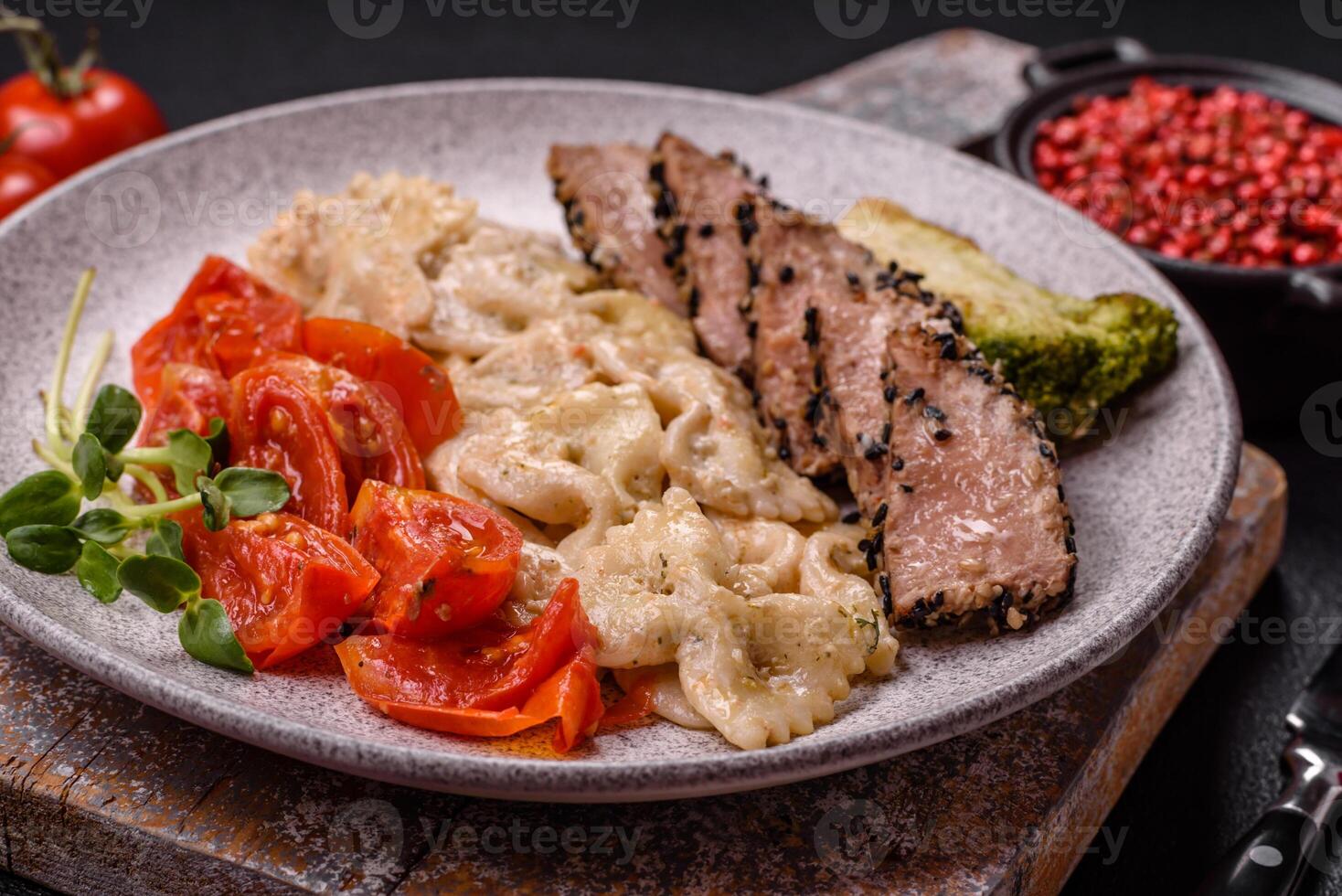 Bowl with slices of baked tuna with broccoli, tomatoes and fusili pasta photo
