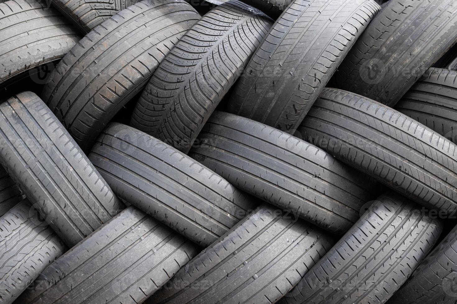A group of used car tires stacked up are waiting to be recycled photo