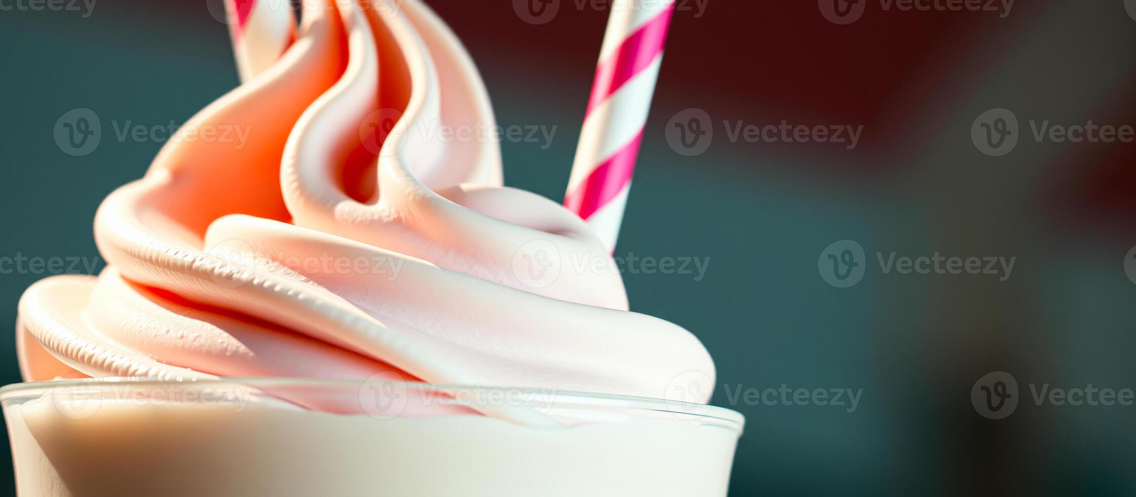 Closeup of a pink milkshake with whipped cream and a red and white straw photo